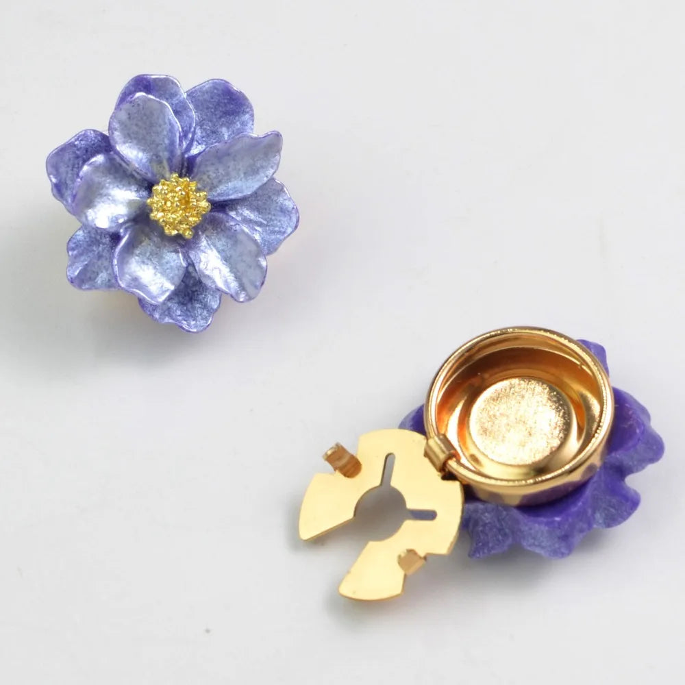 A small, purple pearlescent flower button cover with a gold center and a matching gold-toned piece.