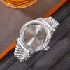 A silver luxury quartz men's wristwatch with a metal bracelet and date display resting on a gray fabric.
