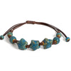 A handmade glazed ceramic star bracelet with blue-green and brown beads on a leather cord.
