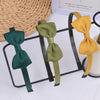 Three decorative grosgrain ribbon hair bows in shades of dark green, olive green, and mustard yellow displayed on a black wir