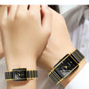 A close-up of a black and gold ceramic fashion wristwatch worn on a wrist.