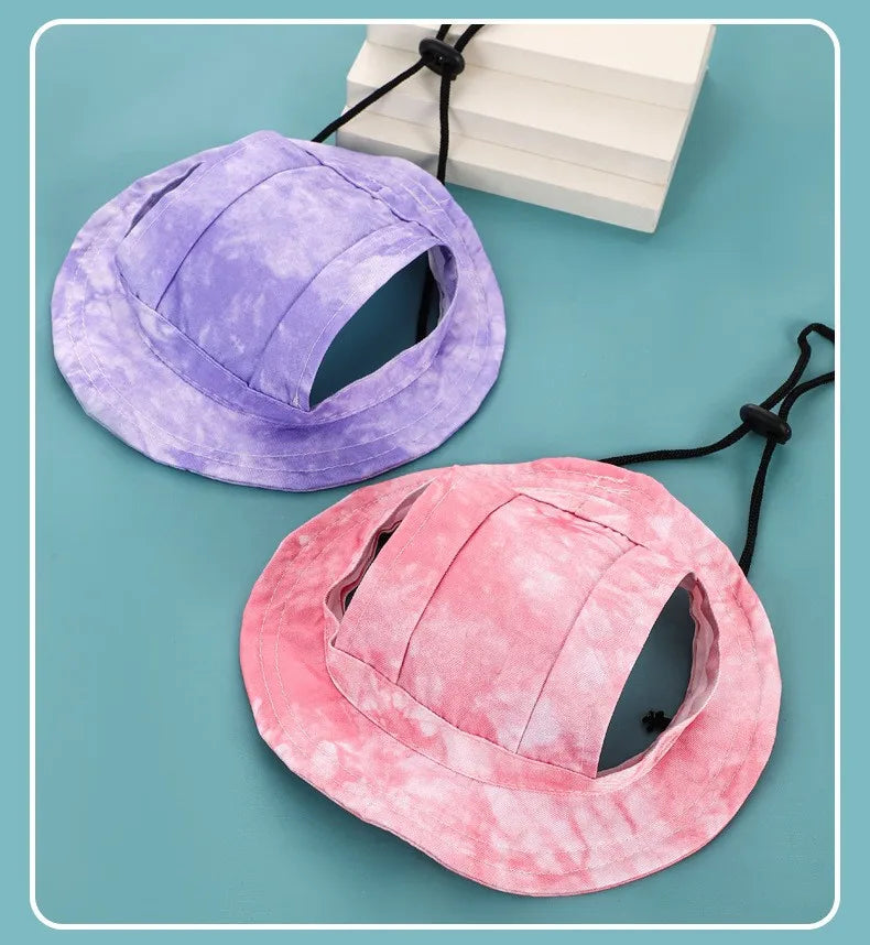 Un chapeau pour animaux de compagnie violet pour chiens et chats à côté d'un rose sur fond bleu clair.