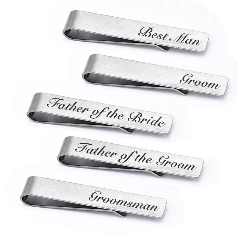 A set of five brushed stainless steel men's tie clips engraved with titles like Best Man, Groom, Father of the Bride, etc.