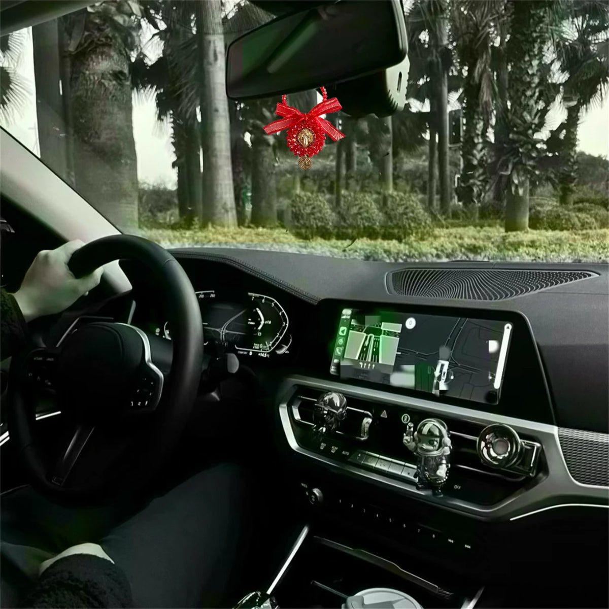 Vista interior de un coche mostrando un juego de colgantes para portabidones con Medalla de San Benito en el tablero.