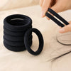 Une main tient une pile de élastiques pour cheveux noirs et un foulard unique sur un fond clair.