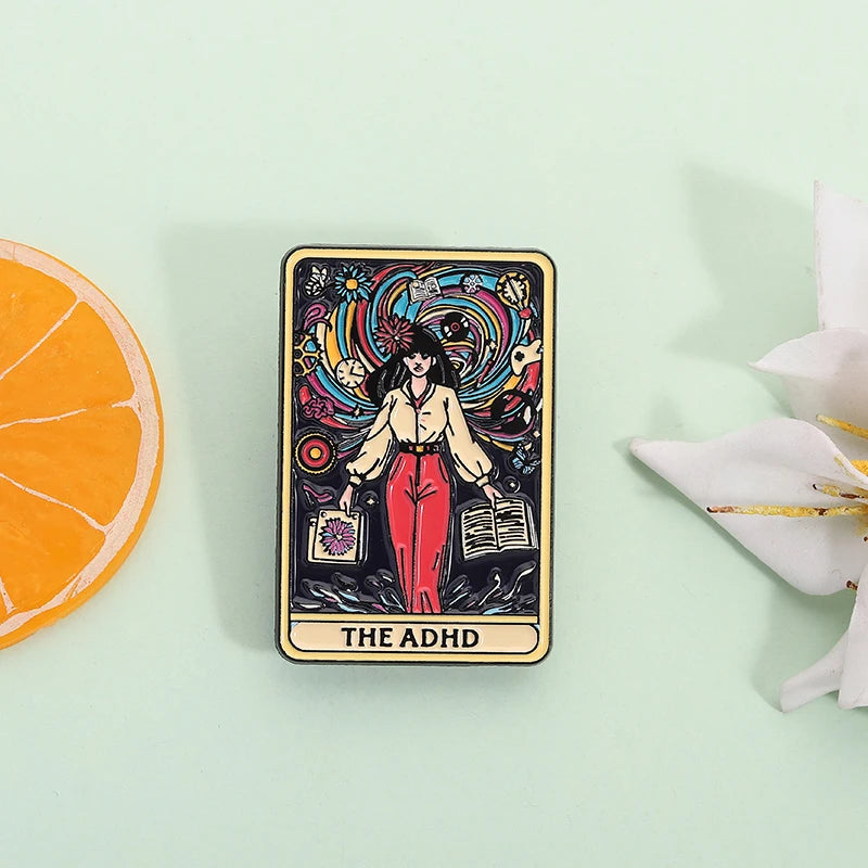 A tarot card enamel pin featuring a woman with flowing hair and colorful cosmic elements, labeled THE ADHD.