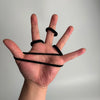 A hand holds several black seamless elastic hair ties, demonstrating their size and texture.