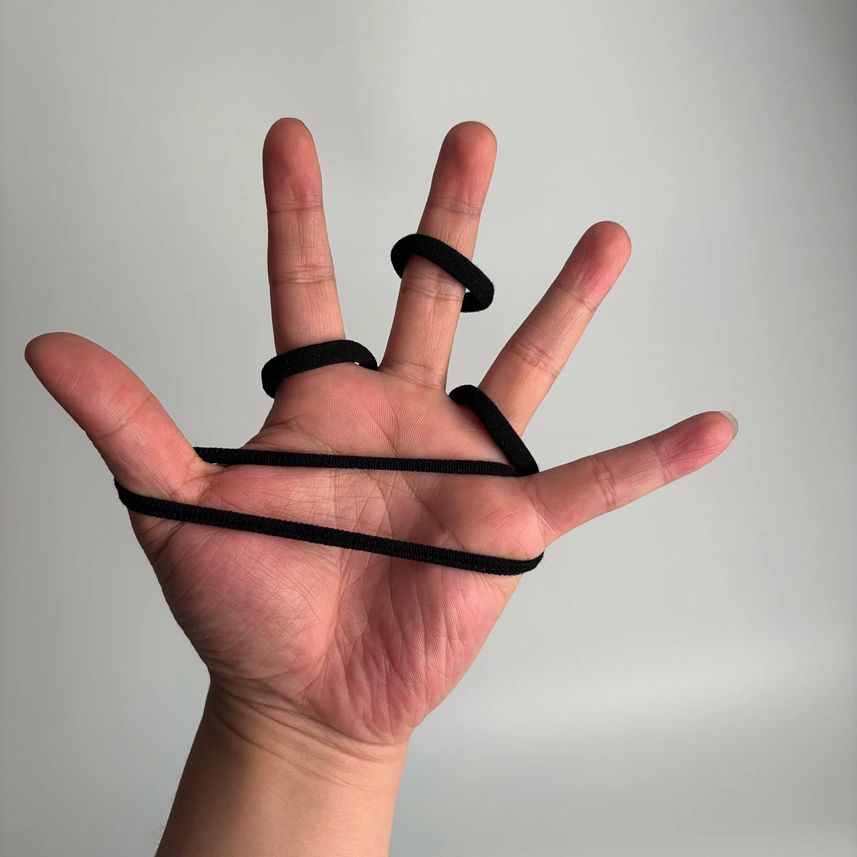 A hand holds several black seamless elastic hair ties, demonstrating their size and texture.