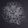 A pile of clear elastic hair ties or rings scattered on a dark surface.
