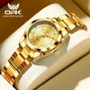 A gold-toned luminous quartz watch with a gold bracelet resting on a light beige surface.