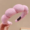 A pink cloud sponge hair accessory headband is being held by a hand.