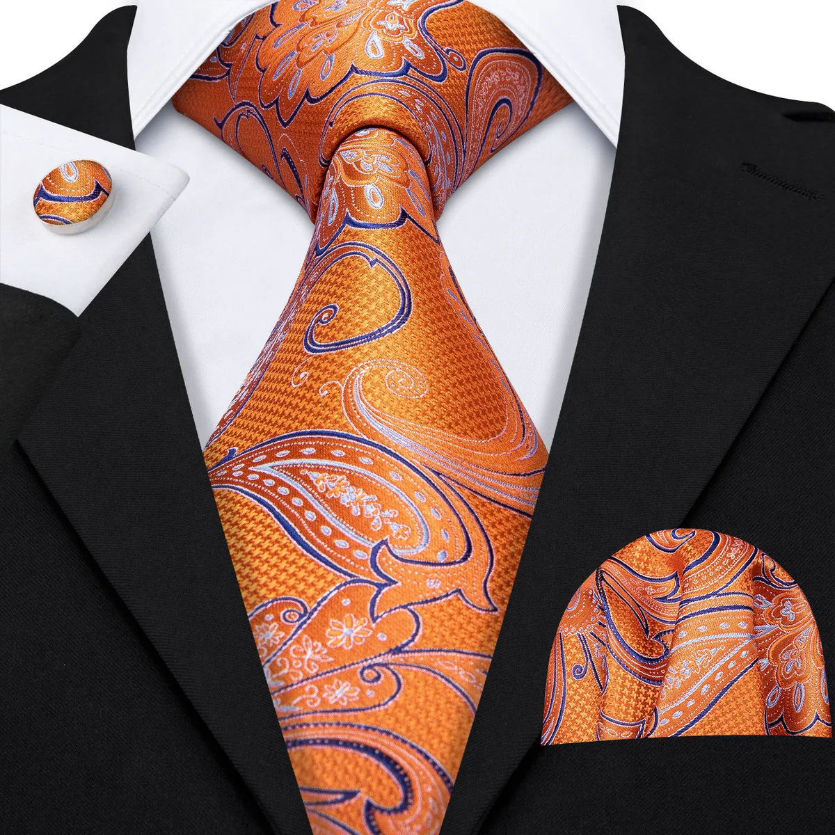 A close-up of an orange and blue patterned silk jacquard tie worn with a black suit jacket and white shirt.