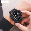 Gros plan d'une montre sportive numérique noire avec un bracelet texturé gris foncé tenue par la main d'une personne.