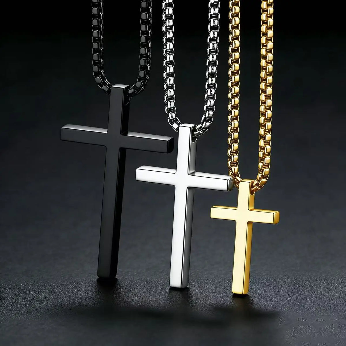 Three stainless steel cross pendant necklaces in black silver and gold metal finishes
