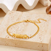 Gold stainless steel Virgo zodiac constellation charm bracelet resting on a light beige surface.