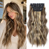Long brown hair with blonde ombre highlights secured by black synthetic clips