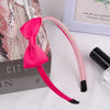 A pink grosgrain ribbon hair bow with black accents is displayed next to a box and a framed picture.