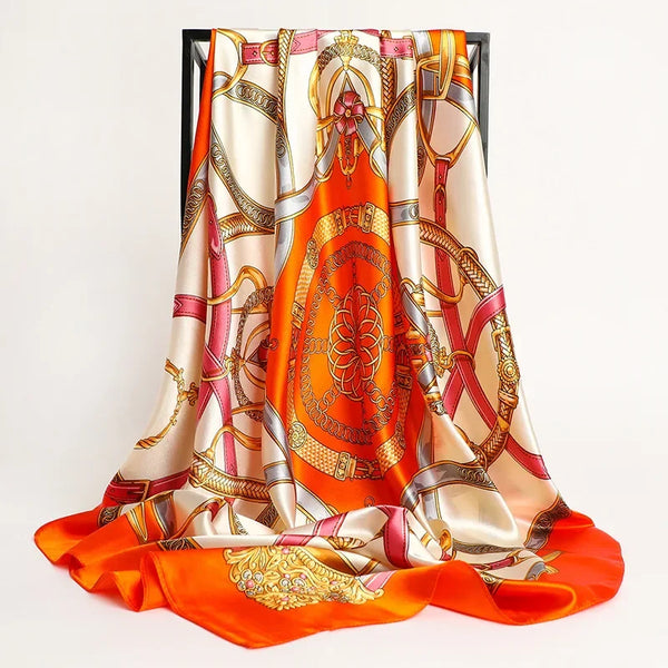 A luxurious satin silk scarf featuring intricate orange and gold patterns with pink accents.