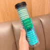 Contenedor de plástico transparente lleno de gomas para el pelo con rayas onduladas verdes, etiquetadas como 'Girl's Rainbow'