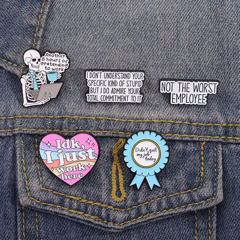 A denim fabric featuring enamel pins with funny work quotes and a heart-shaped pin that says Idk I just work here