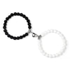 A pair of natural stone heart couple bracelets, one black beaded and one white beaded.