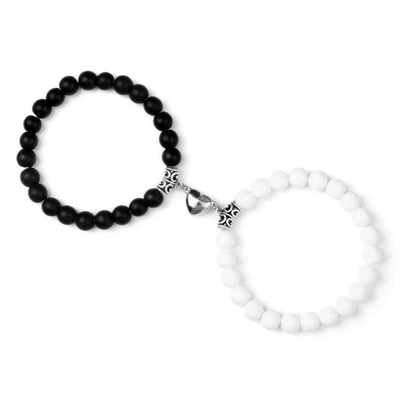 A pair of natural stone heart couple bracelets, one black beaded and one white beaded.