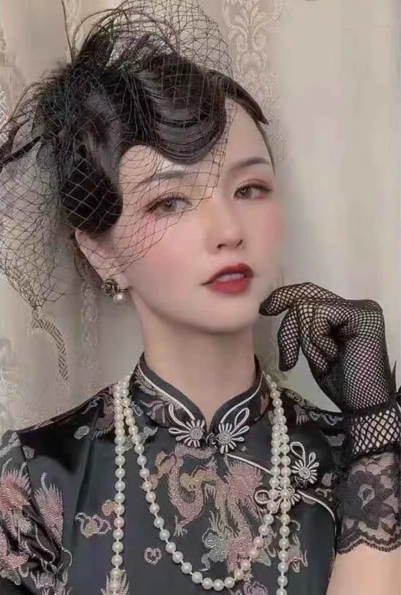 A close-up portrait of a woman wearing sheer lace fishnet evening gloves and traditional attire.