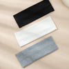 A pack of three solid color fashion headbands in black, white, and gray laid diagonally on a light beige background.