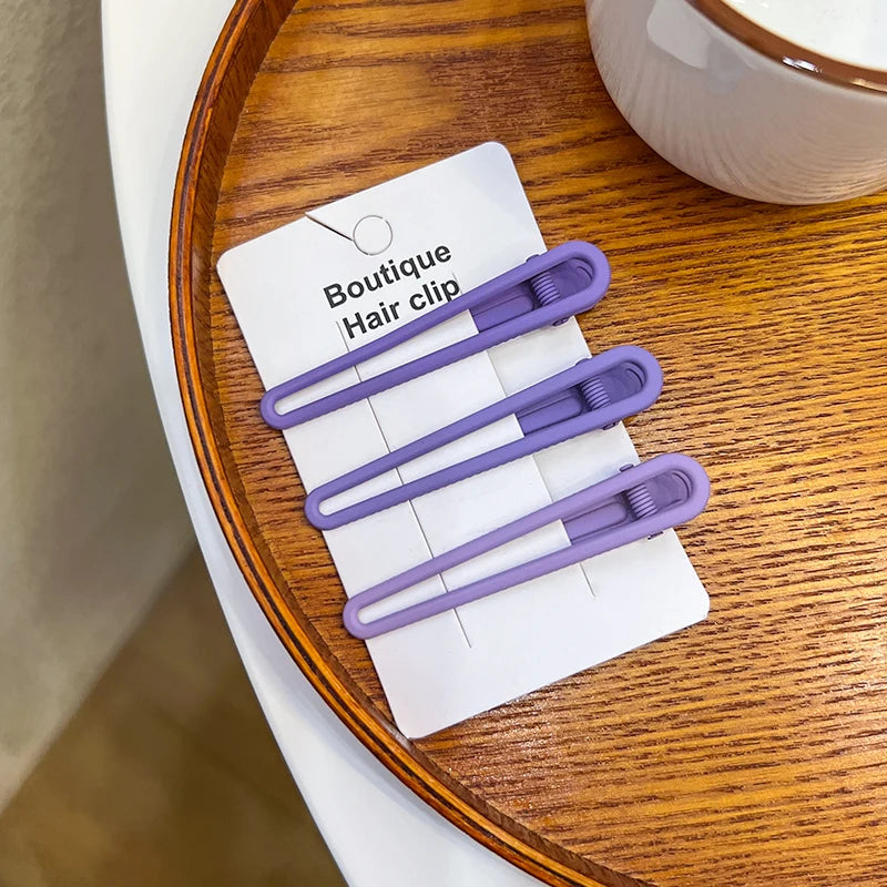 A set of vintage frosted geometry hair clips displayed on a white card on a wooden surface.
