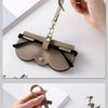 Étui pour lunettes en cuir PU marron embossé avec une sangle en cuir, sur fond blanc.