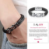 A close-up of a black leather knot bracelet worn on a wrist, with a personalized engraving 'Love My Son' visible.