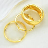 A set of three gold geometric wave bangles stacked together on a white background.