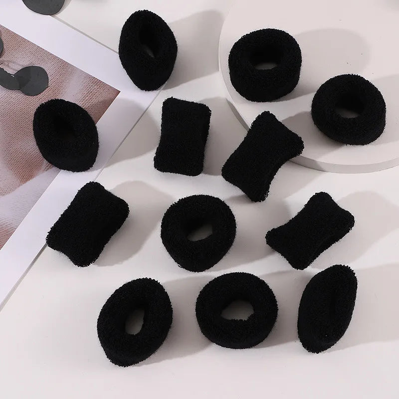 A collection of black cotton elastic hair ties in various sizes and shapes for ponytails and headbands.