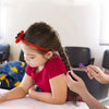A young girl is using an easy hair elastic and rubber band remover tool on her hair.
