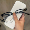 A hand holds a pair of black eyeglasses with gold accents against a white background.