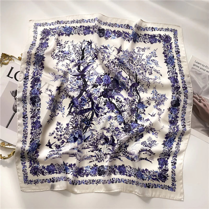 A white silk scarf featuring a detailed purple floral and botanical print.