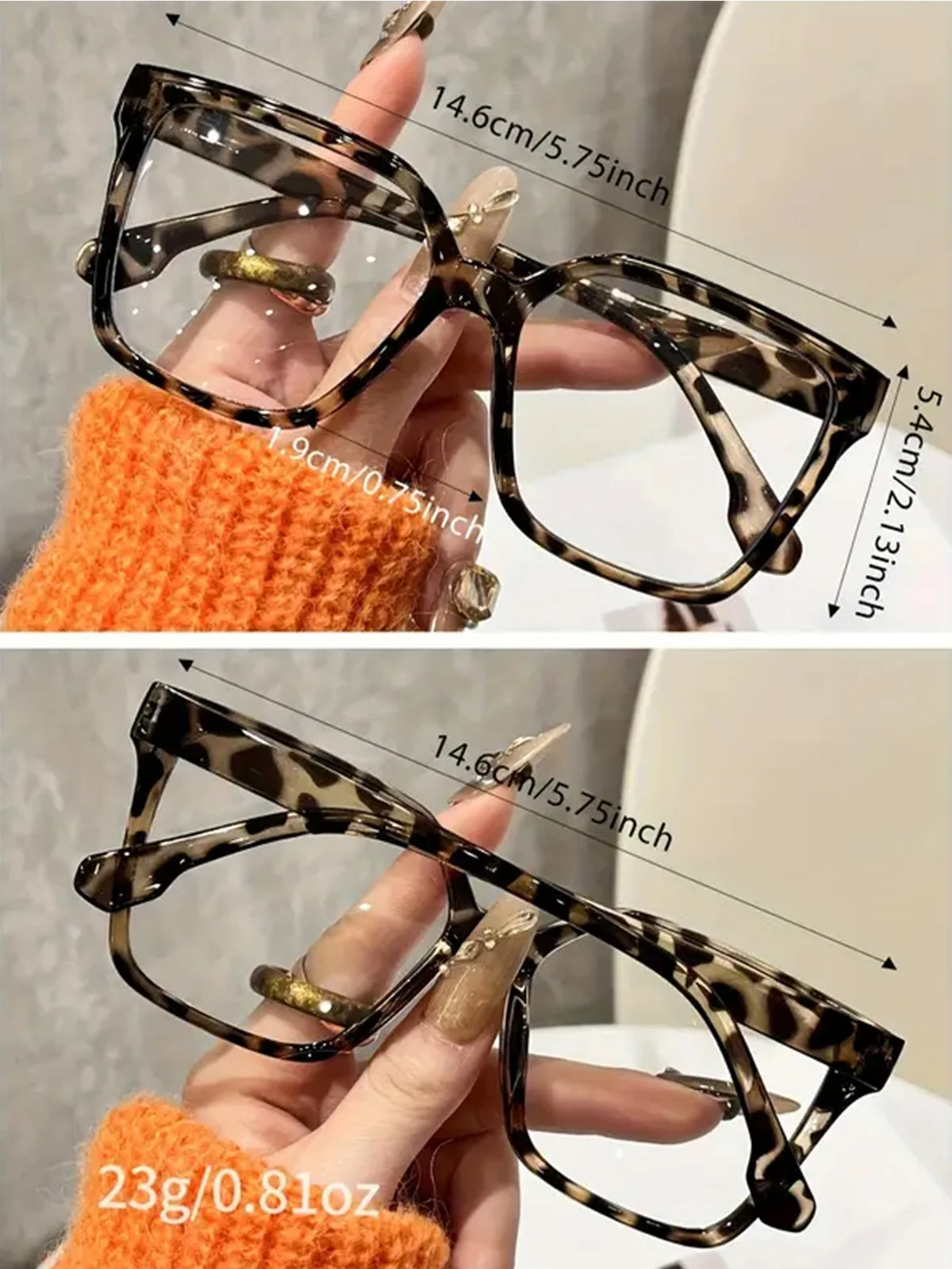 A pair of tortoiseshell reading glasses with clear lenses being held by a hand against an orange knitted background.