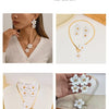 A gold-toned floral pendant necklace and matching earrings set displayed on a white background.