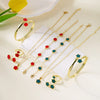 A set of five gold-colored bracelets and rings featuring red and blue enamel plum blossom designs displayed on a white surfac