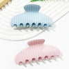 A set of light blue and pink striped plastic hair clips resting on a white surface.