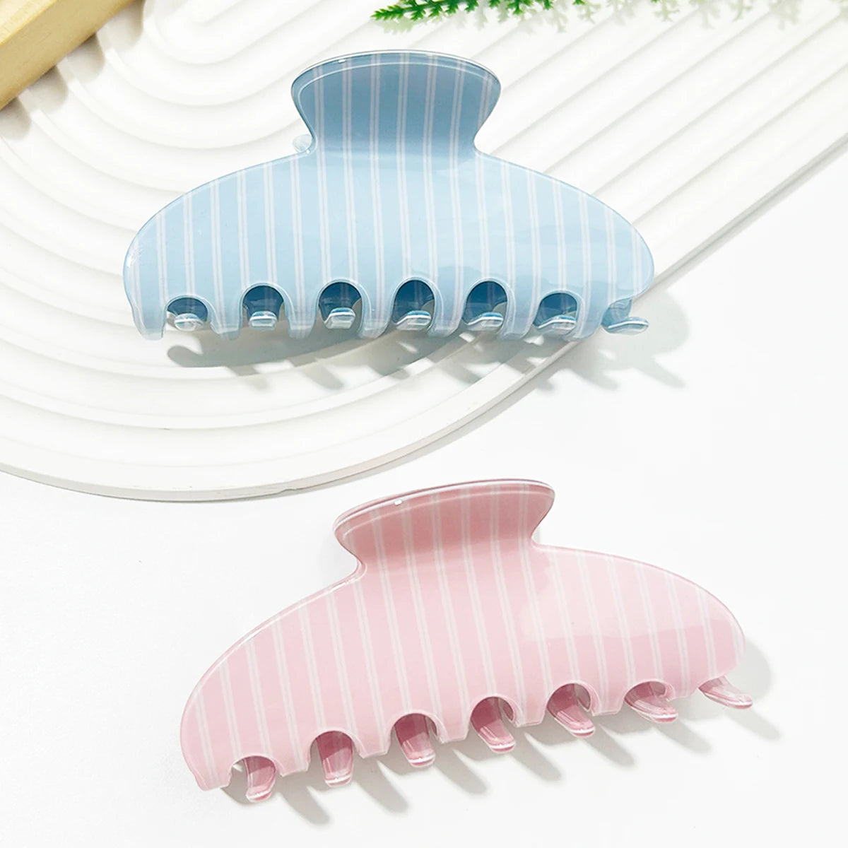 A set of light blue and pink striped plastic hair clips resting on a white surface.