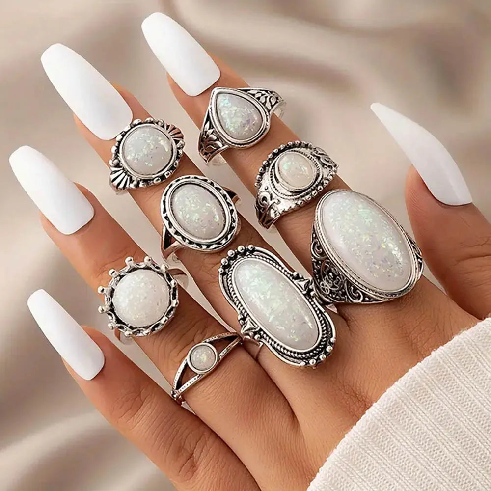 A hand wearing several silver rings featuring white natural stone charms on fingers