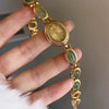 Une main tient une élégante montre-bracelet en or avec des pierres de quartz jade vert sur un bracelet en or.