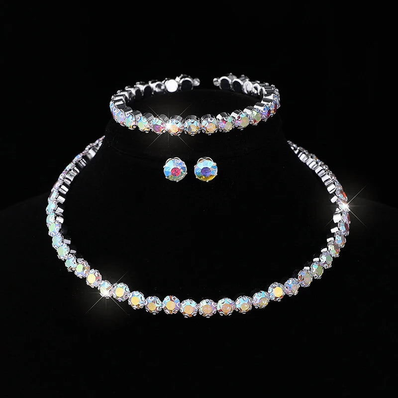 A set of four crystal jewelry pieces including a bracelet, necklace, and earrings displayed against a black background.