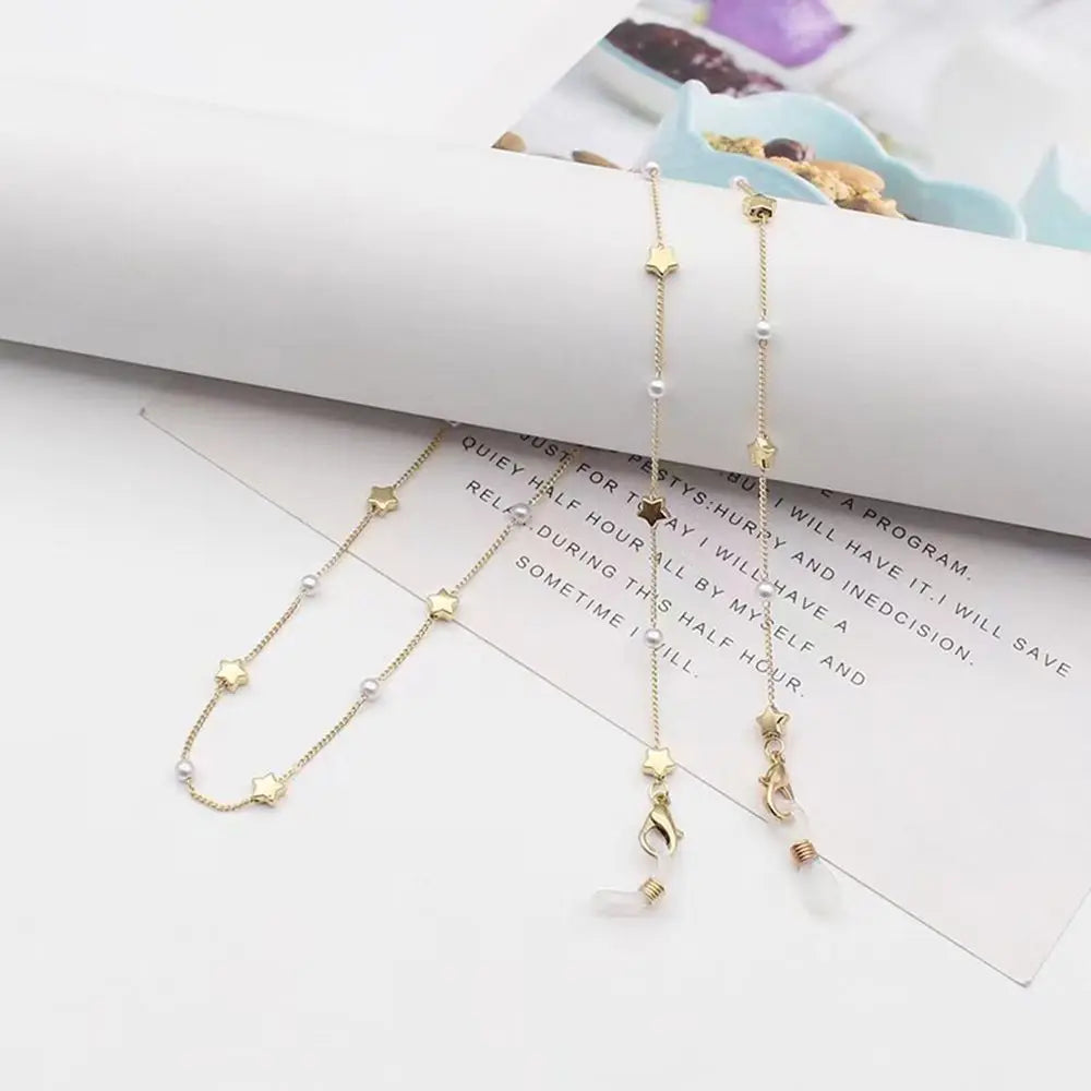 A delicate pearl chain lanyard is displayed on a white background next to a piece of paper.