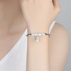 A close-up of a stack of clear diamond and silver bell bangles worn on a wrist.