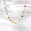 A delicate gold chain necklace featuring irregular colored gemstone charms like blue, purple, and red heart shapes.