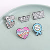 A collection of enamel pins featuring funny work quotes on a light gray background.