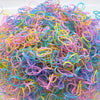 A pile of colorful disposable hair scrunchies in various shades of pink, blue, yellow, and purple.