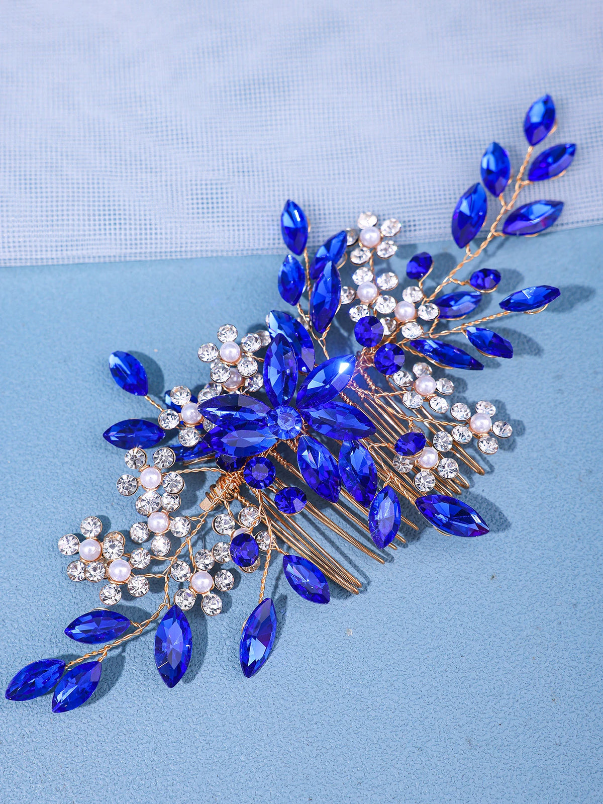 A delicate accessory featuring blue gemstones and clear pearls arranged in a floral design for hair.
